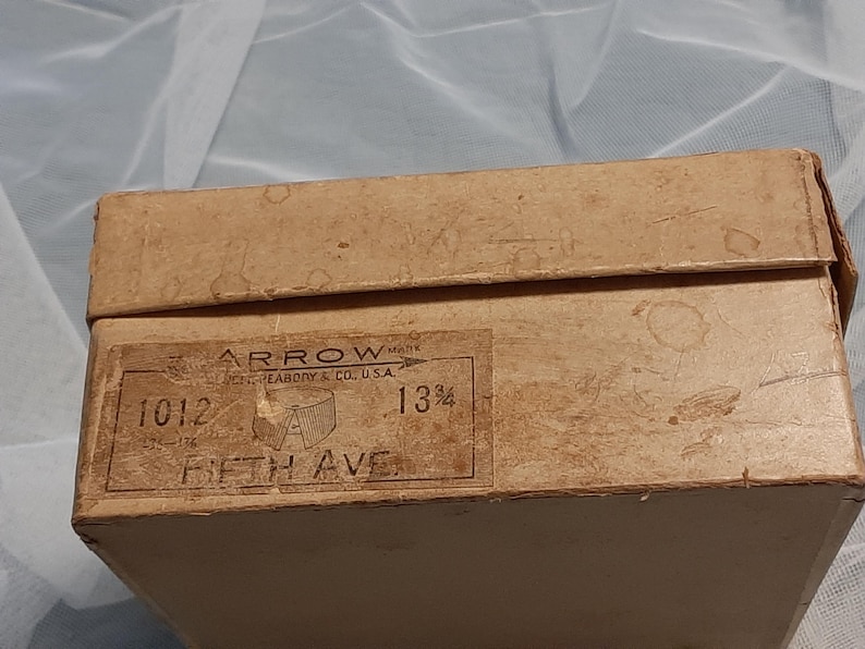May include: A brown cardboard box with the text "ARROW" and "13 1/2" printed on it. The box also has the text "1012 FIFTH AVE" printed on it.