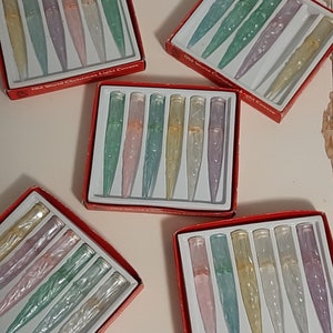May include: Six boxes of Old World Christmas Light Covers. Each box contains six iridescent glass light covers in various colors, including pink, green, and blue. The boxes are red with white lettering.