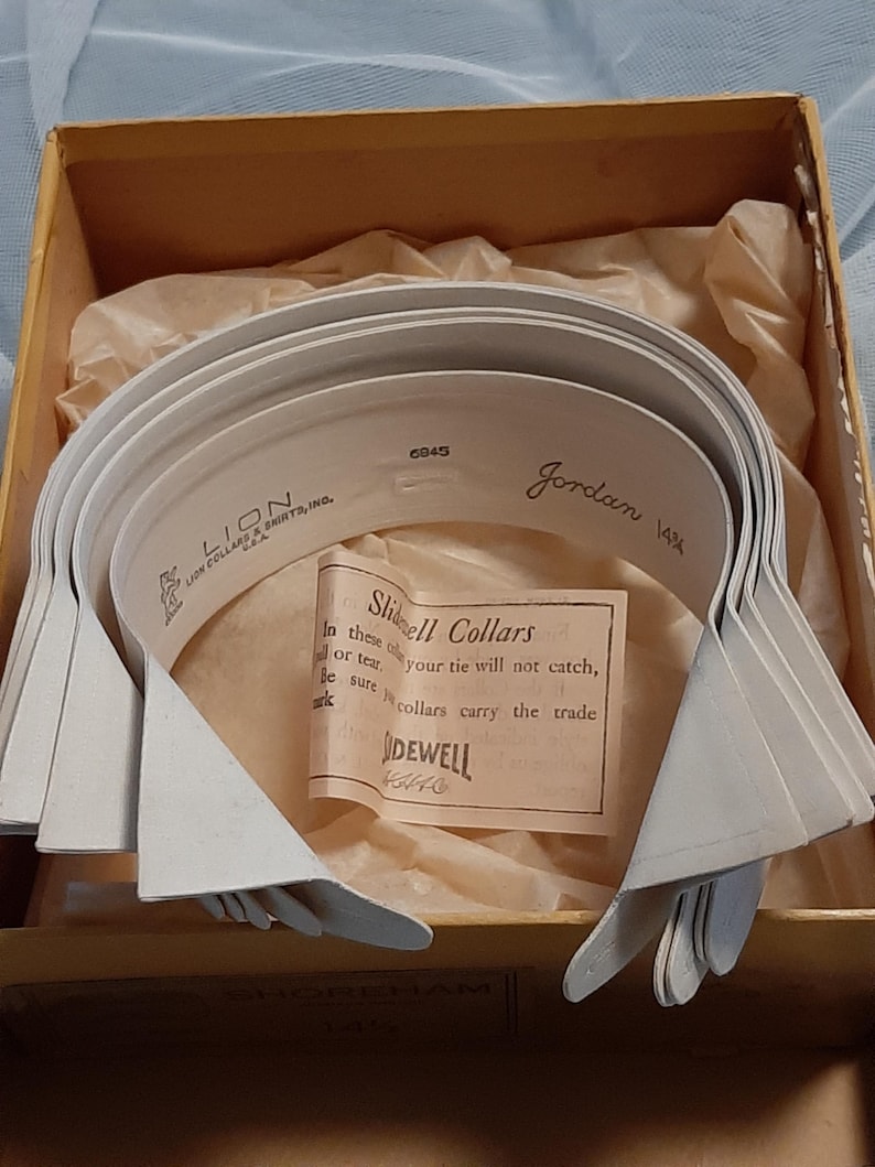 May include: A box of white Slidell Collars in a brown box with the text "Slidell Collars" and "Sidewell" on a label. The box also has the text "Lion Collar & Shirts, Inc." and "Jordan 14 1/2".