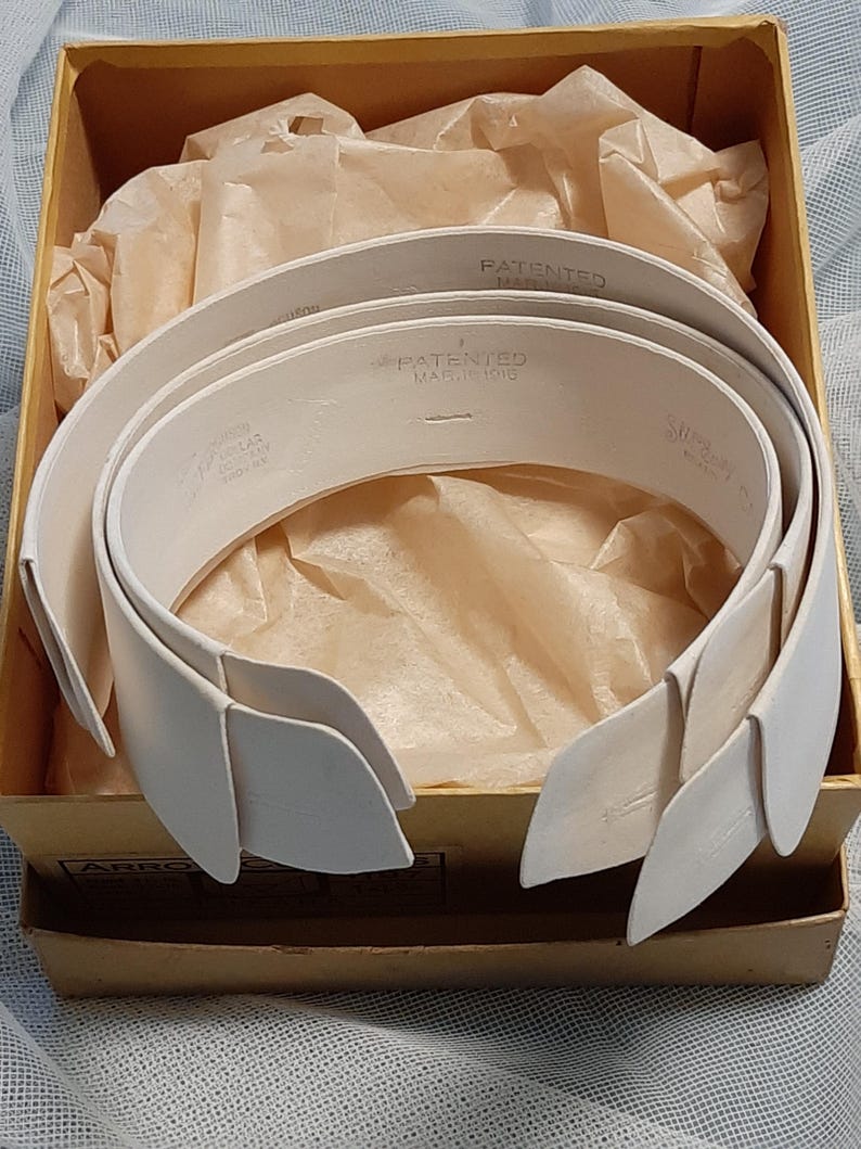 May include: A set of three white, stiff, collar inserts in a cardboard box. The inserts are labelled "PATENTED MARCH 1916".