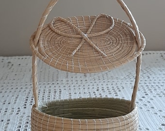 Puede incluir: Una cesta tejida con tapa y asa. La cesta está hecha de materiales naturales y tiene un color marrón claro.