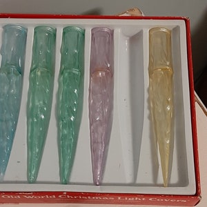 May include: A set of six vintage Christmas light covers in a red box. The covers are made of clear plastic and have a frosted, icicle-like design. The covers are in various colors, including blue, green, purple, and yellow.