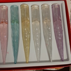 May include: A set of six icicle light covers in various colors, including pink, blue, yellow, white, and purple. The covers are packaged in a red box with the words "Light Covers" printed on the top.