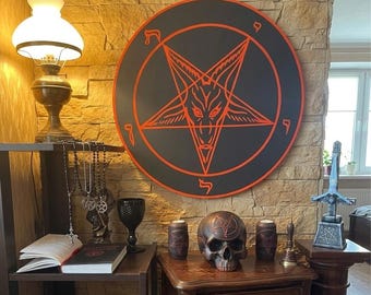 May include: A large circular black wall plaque featuring a red pentagram with a goat head design and Hebrew characters. The display includes a dark skull with a matching pentagram, two cylindrical candles, a black goblet, and a book with a red symbol.