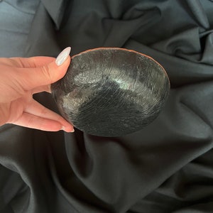 K&ouml;nnte beinhalten: Eine schwarze Keramiksch&uuml;ssel mit strukturierter Oberfl&auml;che. Die Sch&uuml;ssel hat einen braunen Rand.