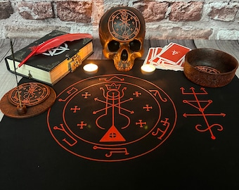 Può includere: Un panno da altare nero con sigilli e simboli rossi, un teschio con un pentagramma sulla fronte, due candele bianche, una piccola ciotola, un mazzo di carte e un libro con una piuma rossa in cima.