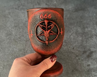 May include: A red and black ceramic goblet with a pentagram and the number 666 on the front.