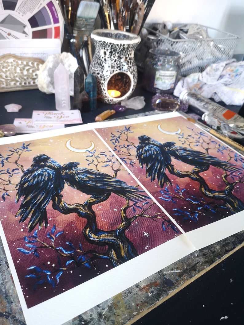 May include: Two black crows perched on a branch with a crescent moon in the background. The painting is done in watercolor and has a dark, mystical feel. The background is a deep purple with blue and gold accents.