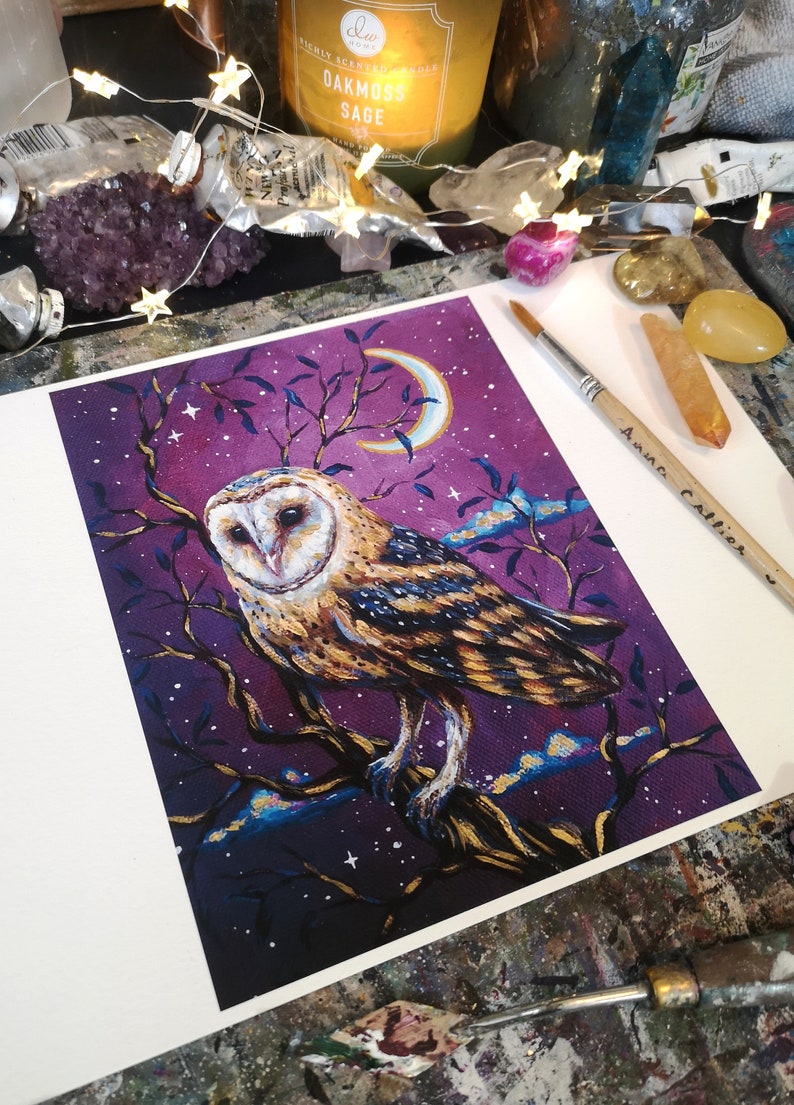 May include: A painting of a barn owl perched on a branch with a crescent moon in the background. The owl is depicted in shades of brown, gold, and white against a purple sky with gold stars. The painting is signed "Anna Collier" in the bottom right corner.