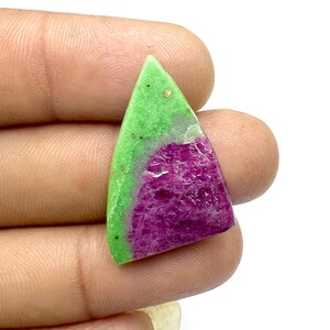 May include: A green and pink gemstone cabochon with a triangular shape. The gemstone has a green top and a pink bottom.