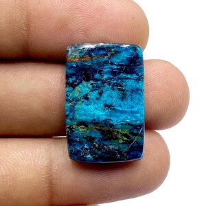 May include: A rectangular, blue and green gemstone with a marbled pattern. The gemstone has a smooth, polished surface.