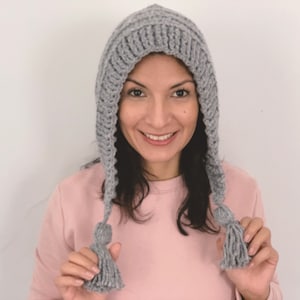 May include: A gray knitted hooded hat with long ties and tassels. The hat is made of a soft, warm yarn and has a simple, classic design.