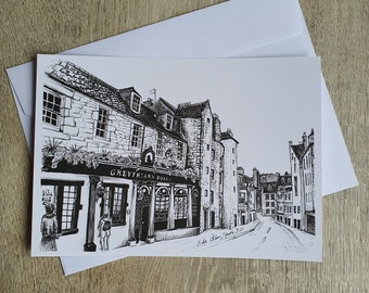 Puede incluir: Dibujo a tinta en blanco y negro de una escena callejera con edificios y un pub llamado "Greyfriars Bobby". El dibujo está en una tarjeta blanca con un sobre blanco.