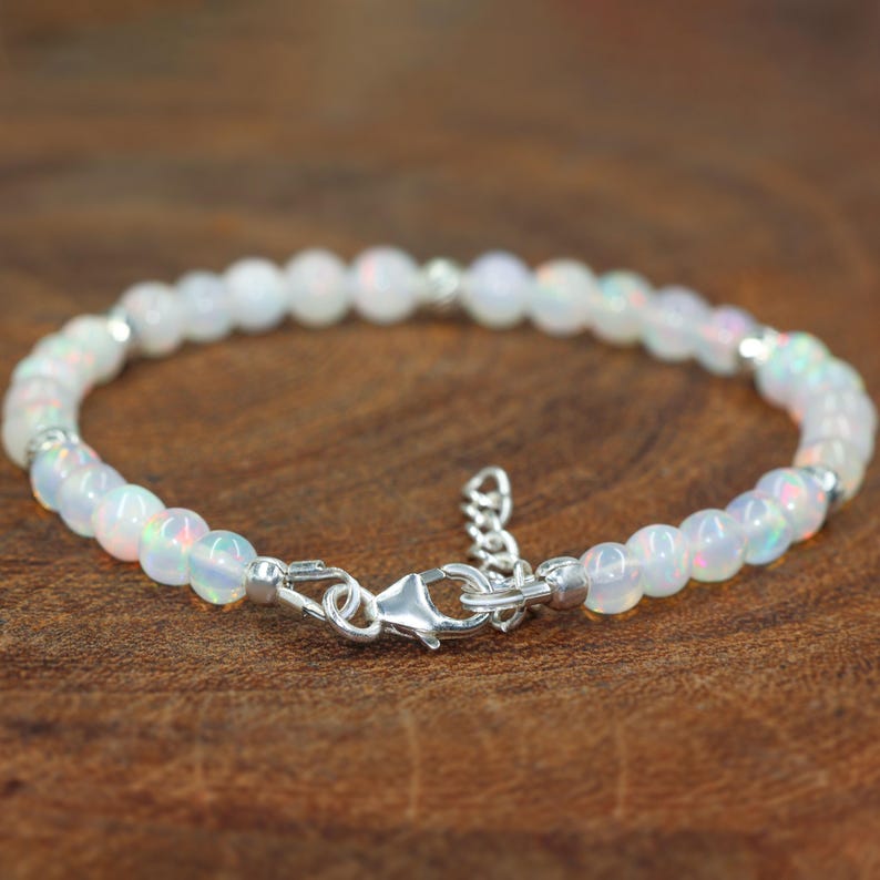 May include: A delicate silver bracelet with white opal beads. The bracelet has a lobster clasp closure.