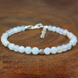 May include: A delicate silver bracelet with a chain closure and white opal beads.