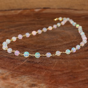 Puede incluir: Un collar delicado hecho con cuentas de ópalo blanco y alambre de oro. El collar mide aproximadamente 45 cm de largo y tiene un cierre simple.