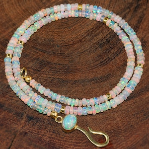 Pode incluir: Um delicado colar de ouro com um pingente de opala. O colar é feito de pequenas contas de opala iridescente e apresenta um design simples e elegante.