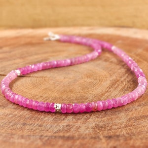 May include: A pink gemstone necklace with silver accents. The necklace is made of small, faceted beads and is strung on a silver chain.