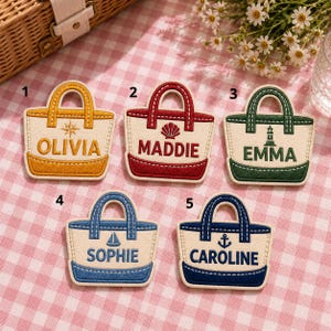 Puede incluir: Cinco parches bordados con forma de bolsos de mano, cada uno con un esquema de color único, un icono náutico y un nombre. Los parches están numerados del 1 al 5 y muestran los nombres Olivia, Maddie, Emma, Sophie y Caroline en letras negritas.