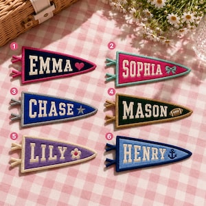 Peut inclure: Six fanions triangulaires en feutrine avec des noms et icônes brodés. Le 1 est bleu marine avec EMMA et un cœur. Le 2 est rose avec SOPHIA et un nœud. Le 3 est bleu avec CHASE et une étoile. Le 4 est vert foncé avec MASON et un ballon de rugby. Le 5 est violet avec LILY et une fleur. Le 6 est bleu clair avec HENRY et une ancre.