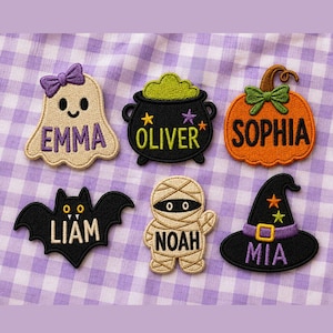 May include: Six embroidered Halloween-themed patches featuring a beige ghost with a purple bow labeled EMMA, a black cauldron with green bubbles labeled OLIVER, an orange pumpkin labeled SOPHIA, a black bat labeled LIAM, a beige mummy labeled NOAH, and a black witch hat labeled MIA.