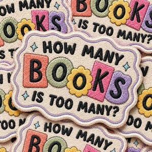 May include: Embroidered patch with the text "HOW MANY BOOKS IS TOO MANY?" in black, with colorful letters and flower accents. The patch has a light beige background and a decorative border. A fun accessory for book lovers.