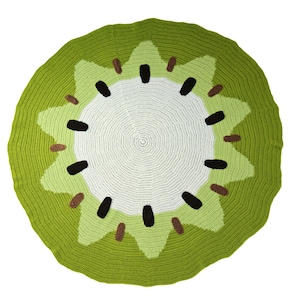 May include: A green and white crocheted rug shaped like a kiwi fruit. The rug has a brown centre with black seeds.