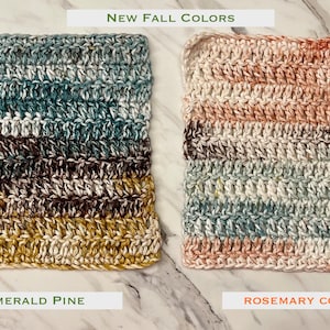May include: Two square crochet washcloths with horizontal stripes. The left cloth, labeled Emerald Pine, features shades of blue, brown, and mustard yellow. The right cloth, labeled Rosemary Cottage, features shades of cream, peach, and sage green.