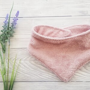 Peut inclure: Une bavette pour bébé en tissu éponge rose avec une fermeture à pression.