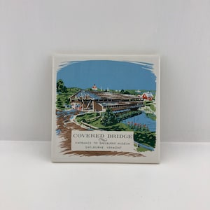 Puede incluir: Azulejo de cerámica cuadrado con una ilustración vintage de un puente cubierto sobre un río. La imagen incluye el texto "COVERED BRIDGE, Entrance to Shelburne Museum, Shelburne, Vermont."