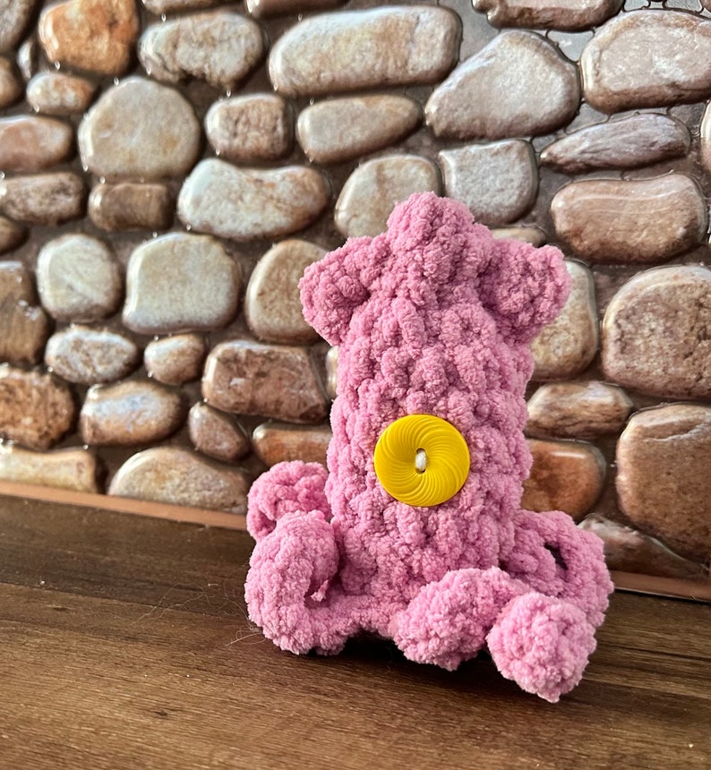 May include: A pink crocheted octopus with a yellow button for an eye.
