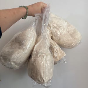 Peut inclure: Plusieurs sacs en plastique transparents remplis d'une substance granulaire de couleur claire. Les sacs sont maintenus ensemble, sugg&eacute;rant une quantit&eacute; importante. Le contenu semble &ecirc;tre un produit alimentaire, peut-&ecirc;tre de la farine ou un ingr&eacute;dient similaire.