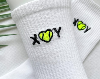 May include: White socks with black embroidery of the letters "XOY" with a heart shape containing a yellow tennis ball in the center.