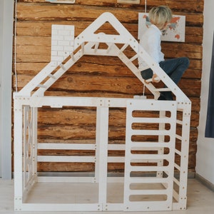 May include: White wooden playhouse with a climbing wall, ladder, and a small window. The playhouse is designed for children to climb and play in.