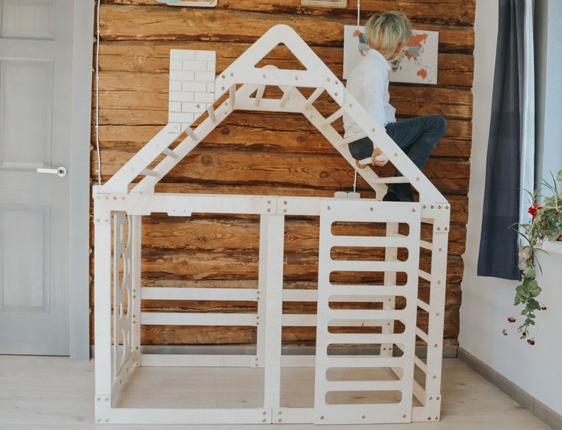 May include: White wooden playhouse with a climbing wall, ladder, and a small window. The playhouse is designed for children to climb and play in.