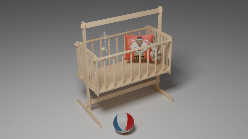 Puede incluir: Una cuna de beb&eacute; de madera de color claro con una almohada decorativa con un dise&ntilde;o de zorro, un peque&ntilde;o oso de peluche y un m&oacute;vil colgante. Una pelota roja, blanca y azul descansa en el suelo frente a la cuna.