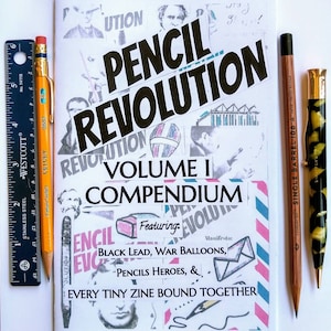 May include: A white booklet with the title "Pencil Revolution Volume I Compendium" featuring black text on a pink and blue background. The booklet is surrounded by pencils, a pencil sharpener, and a pocket knife.