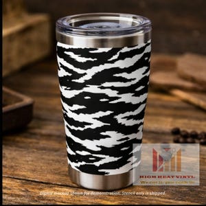 May include: A stainless steel tumbler with a black and white zebra stripe pattern. The tumbler has a clear lid and a silver base. The text "HIGH HEAT VINYL We cut it, you cook it" is visible. The text "Digital mockup shown for demonstration. Stencil only is shipped." is also visible.
