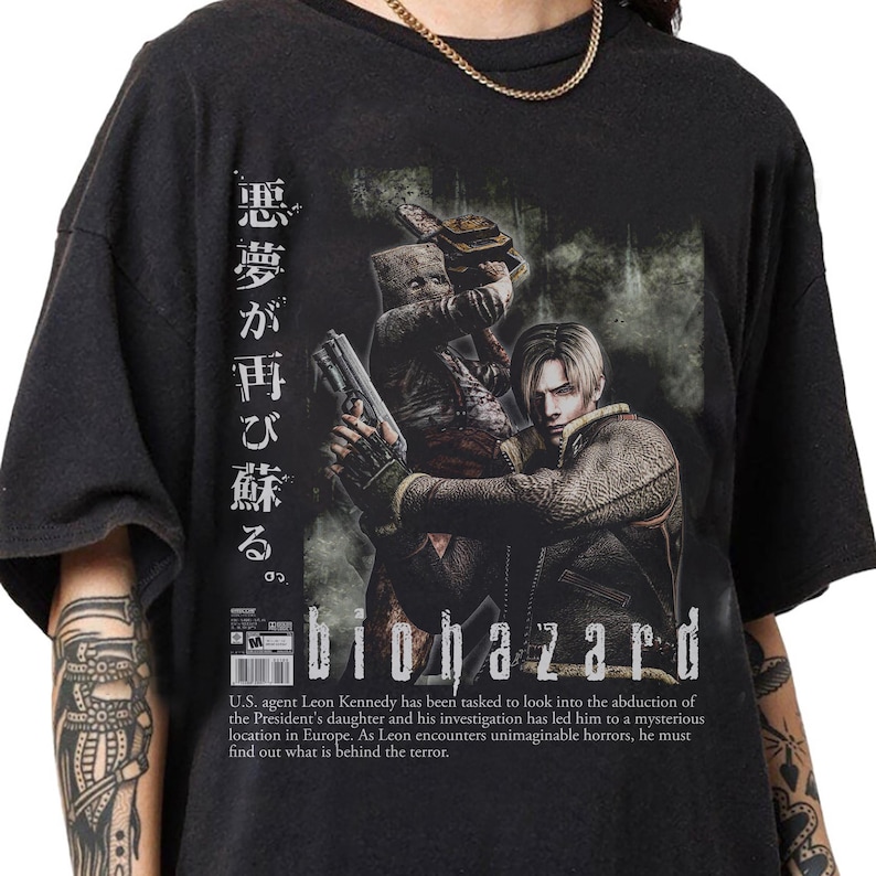 Op de afbeelding: Zwart t-shirt met een afbeelding van de videogame Biohazard. Het ontwerp bevat een personage met een pistool, Japanse tekst en het woord "biohazard" in het wit. Het shirt heeft ook een beschrijving van het spel.