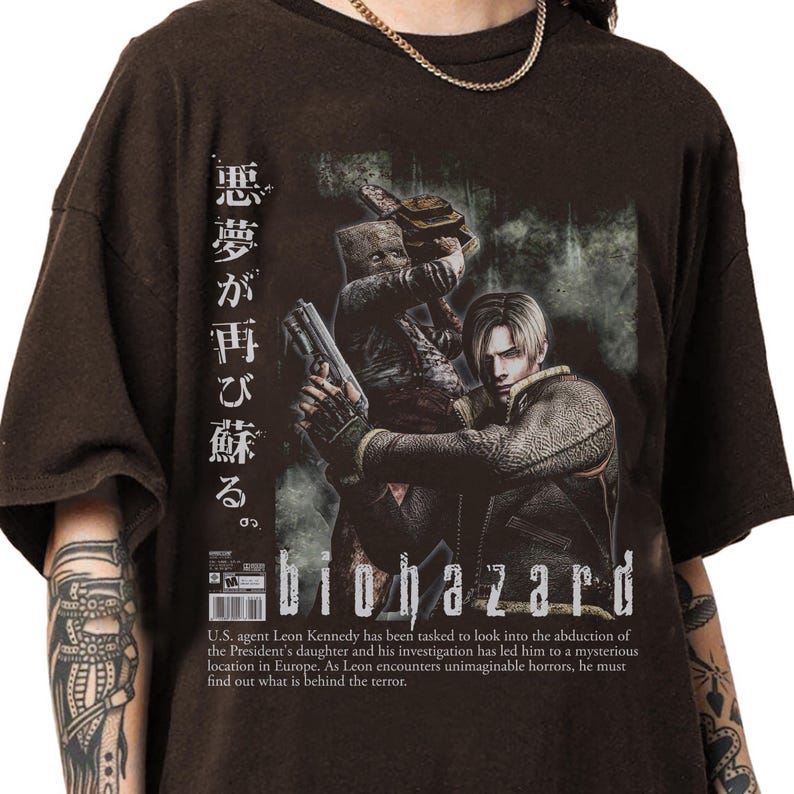 Op de afbeelding: Bruin t-shirt met een "Biohazard" graphic. Het ontwerp toont een personage met een pistool, Japanse tekst en de titel van het spel. De tekst eronder beschrijft de plot van het spel.