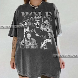 May include: Dark gray t-shirt featuring a collage of black and white images of a person. The word "ROLE" is printed at the top, with "Model" below it. The text "THEPRIDEOFVIETNAM" is printed on the shirt.
