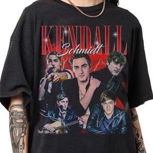 Könnte beinhalten: Schwarzes T-Shirt mit einem Retro-Grafik von Kendall Schmidt. Das Design zeigt ein Porträt des Sängers und den Namen "Kendall Schmidt" in einer Vintage-Schrift vor einem roten Blitzhintergrund.