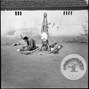 Pode incluir: Uma fotografia a preto e branco de duas pessoas a praticar yoga ao ar livre. Uma pessoa está de pé na cabeça, enquanto a outra está sentada no chão. A fotografia foi tirada em frente a uma parede branca com janelas.
