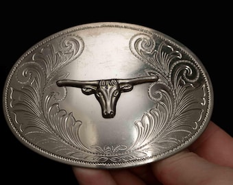 May include: Silver belt buckle with an engraved design of a longhorn steer head.