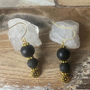 May include: A pair of earrings with a clear quartz crystal, black beads, and gold accents.