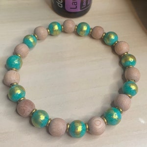 May include: A wooden bracelet with teal and gold beads. The beads are round and have a smooth finish.