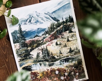 Puede incluir: Pintura acuarela de una cordillera con un pico nevado. La pintura presenta un exuberante bosque verde en primer plano con un arroyo que lo atraviesa. El fondo muestra un cielo azul con nubes blancas. La pintura está firmada "Ann C. Olsen" en la esquina inferior derecha.