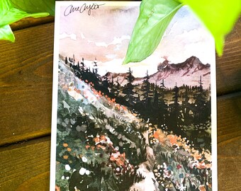 Puede incluir: Pintura acuarela de un sendero de montaña con flores silvestres y un bosque en el fondo. El cielo es de un rosa y naranja suave. La pintura está firmada "Amethyst".