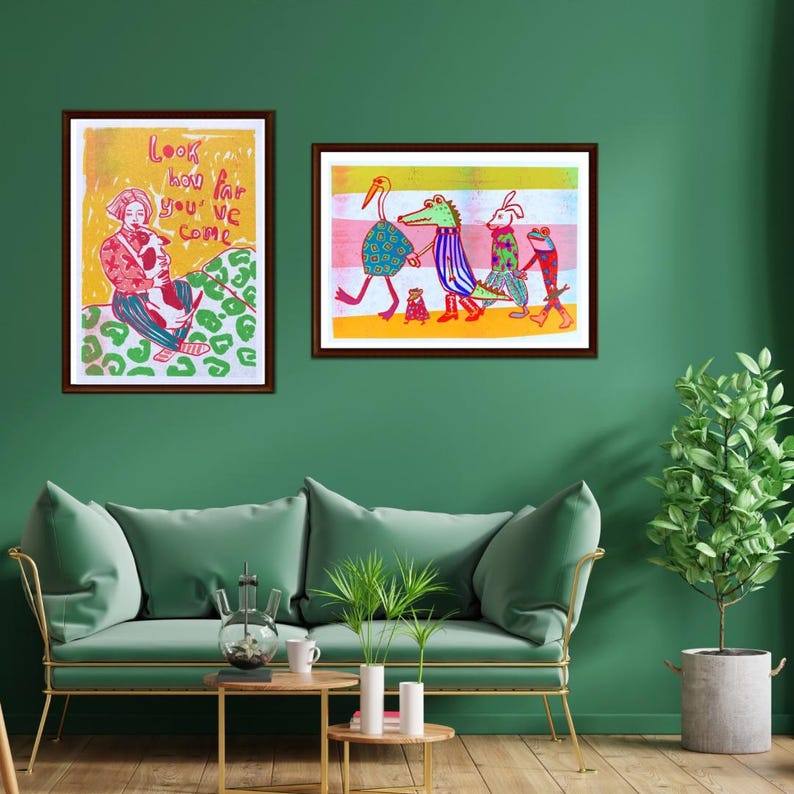 K&ouml;nnte beinhalten: Zwei gerahmte Illustrationen an einer gr&uuml;nen Wand. Die linke Illustration zeigt eine Person, die einen Hund h&auml;lt, mit dem Text "Look how far you've come". Die rechte Illustration zeigt eine Gruppe von Tieren, die zusammen gehen, darunter ein Storch, ein Alligator, ein Kaninchen und ein Frosch.