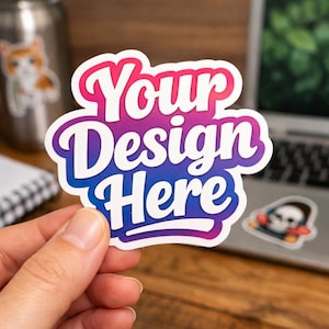 Può includere: Un adesivo bianco con un gradiente rosa, viola e blu, con la scritta "Your Design Here" in un carattere audace e stilizzato. L'adesivo è tenuto in mano, con un computer portatile e altri adesivi sullo sfondo.